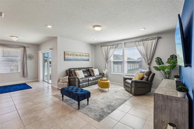 living room with visible vents, a textured ceiling, baseboards, and light tile patterned floors