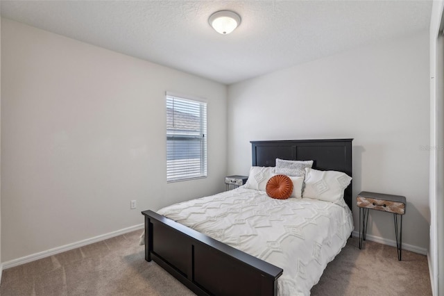 bedroom featuring baseboards, a textured ceiling, and light colored carpet