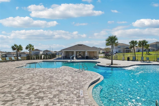 pool with a lawn, a patio, a residential view, an outbuilding, and fence