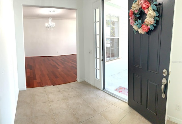 tiled entryway featuring crown molding and a notable chandelier