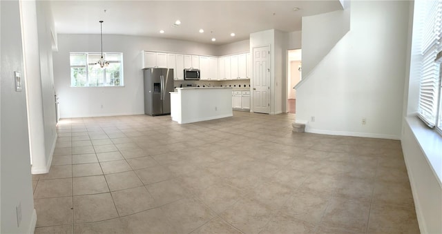 kitchen with pendant lighting, white cabinets, a center island, stainless steel appliances, and light tile patterned floors