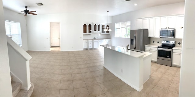 kitchen featuring stainless steel appliances, white cabinetry, a kitchen island with sink, and decorative light fixtures