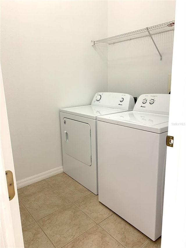 clothes washing area featuring light tile patterned floors and washing machine and clothes dryer