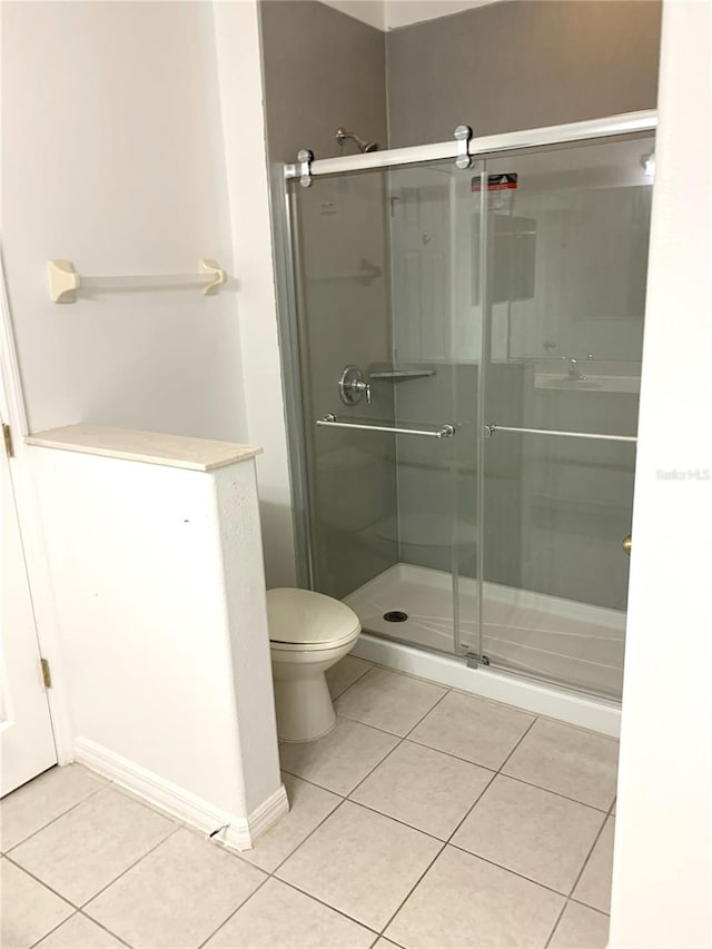 bathroom with toilet, tile patterned floors, and an enclosed shower