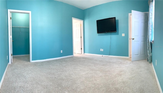 unfurnished bedroom featuring a closet, light colored carpet, and a spacious closet