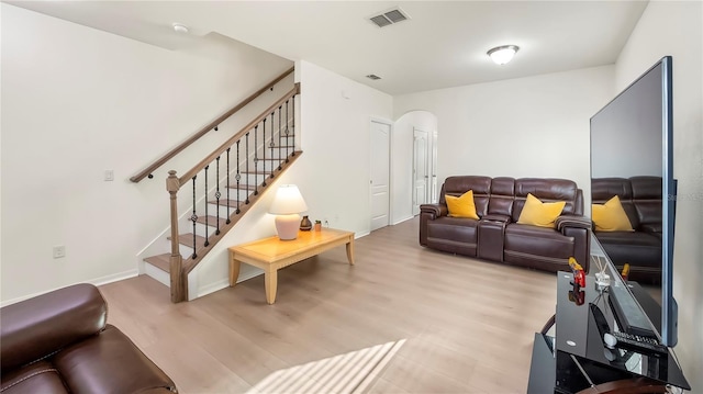 living room featuring stairs, light wood-type flooring, and visible vents