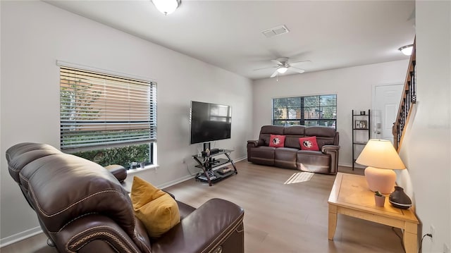 living room with visible vents, ceiling fan, wood finished floors, baseboards, and stairs