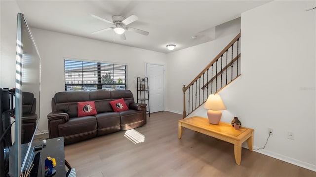 living room with stairway, wood finished floors, a ceiling fan, and baseboards