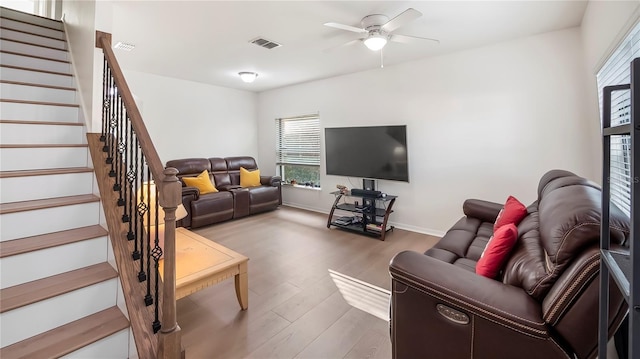 living area with visible vents, stairway, a ceiling fan, wood finished floors, and baseboards