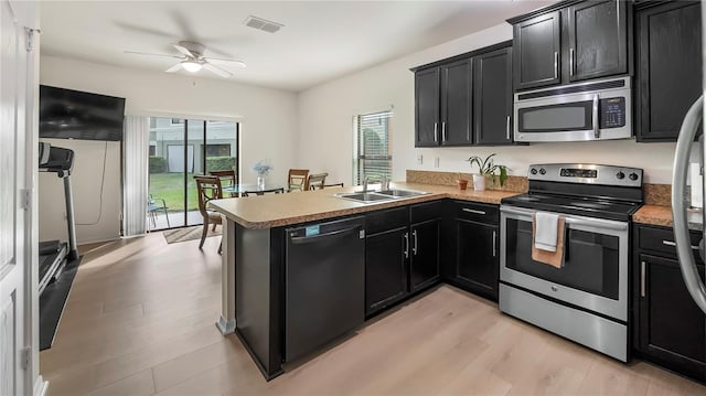 kitchen with appliances with stainless steel finishes, visible vents, dark cabinets, and a peninsula