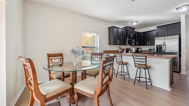 dining room featuring light wood-style flooring and baseboards