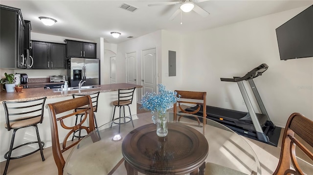 kitchen with dark cabinetry, visible vents, a sink, stainless steel fridge, and a kitchen bar