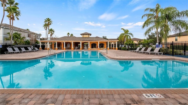 community pool with a patio and fence