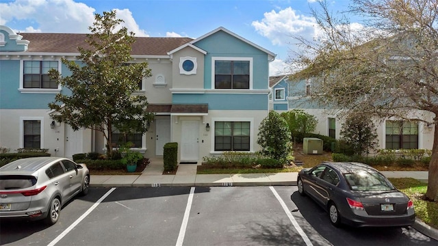 view of property featuring uncovered parking and stucco siding