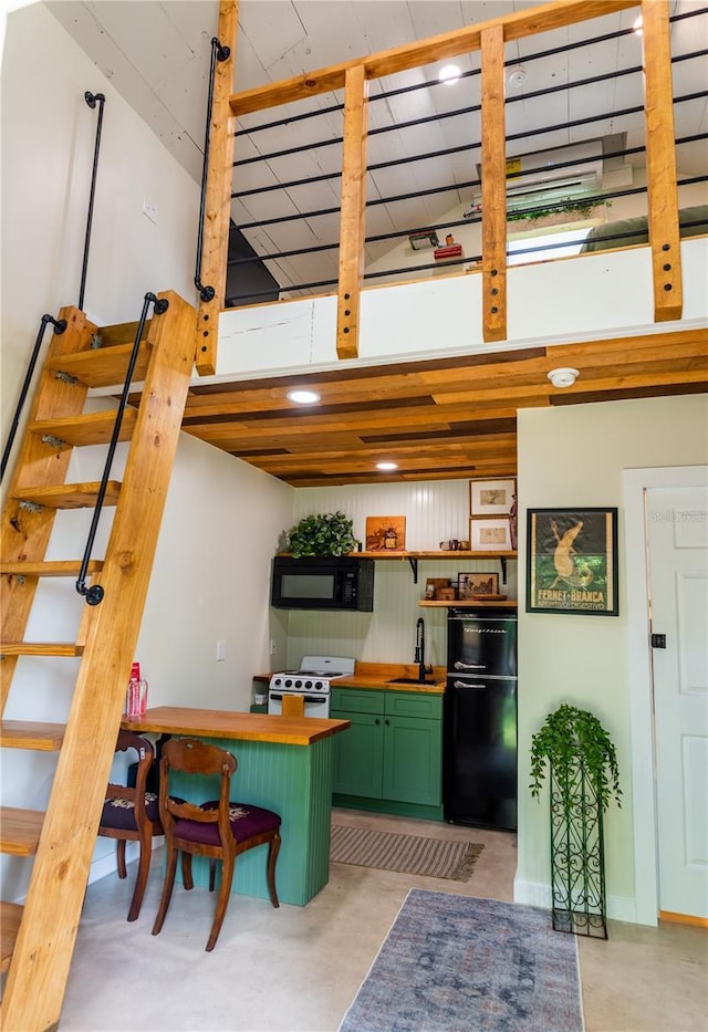 kitchen featuring white gas stove, sink, a kitchen breakfast bar, green cabinets, and fridge