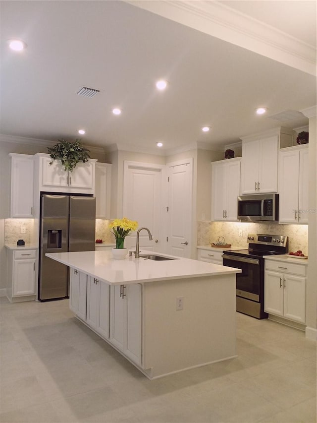 kitchen featuring tasteful backsplash, stainless steel appliances, a kitchen island with sink, sink, and white cabinets