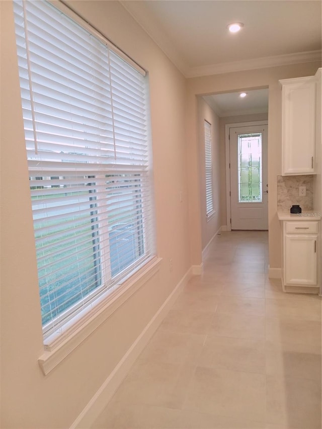 hall featuring light tile patterned floors and crown molding