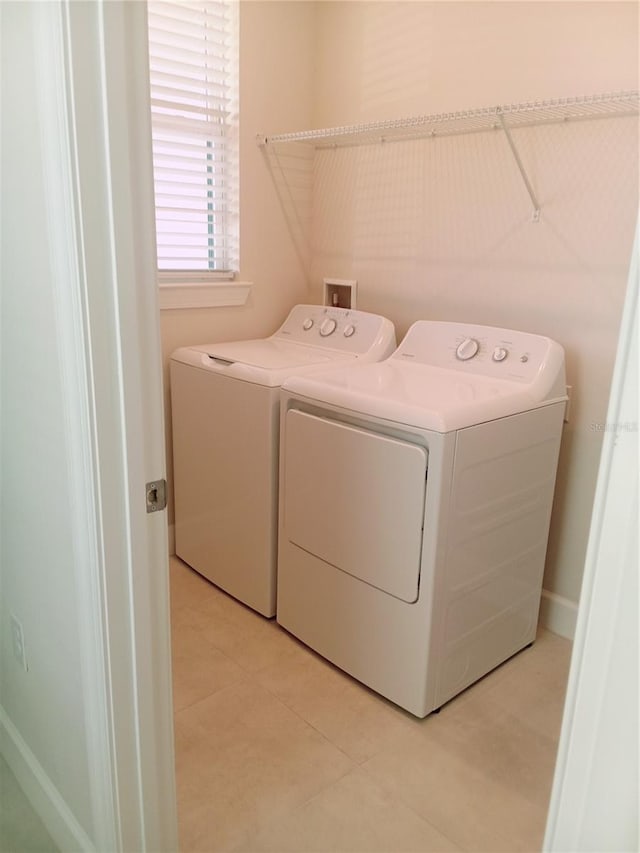 clothes washing area featuring washer and dryer and light tile patterned floors