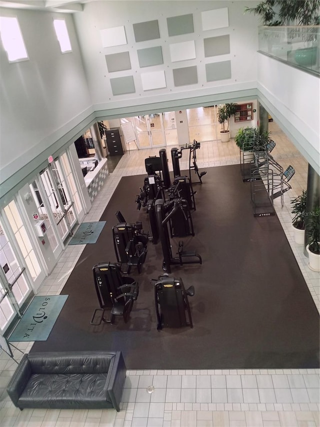 gym featuring a towering ceiling and tile patterned floors