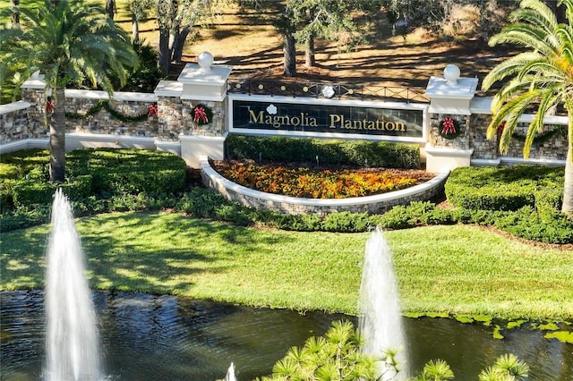 community sign with a water view and a yard