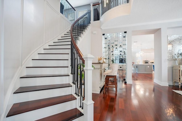 staircase with wood-type flooring and crown molding