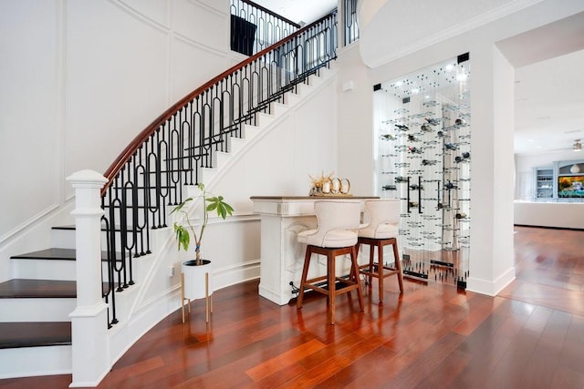 stairway with wood-type flooring and crown molding