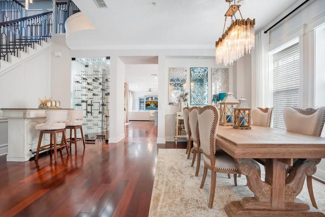 dining area with wood-type flooring, an inviting chandelier, and ornamental molding