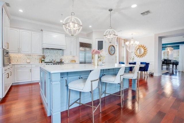 kitchen with stainless steel built in refrigerator, white cabinets, and a spacious island