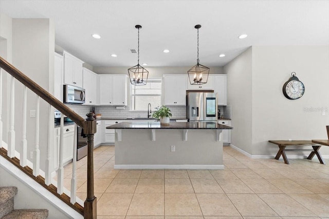 kitchen with a kitchen bar, white cabinetry, a center island, and stainless steel appliances