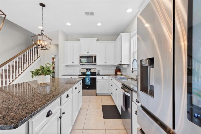 kitchen featuring a center island, a notable chandelier, light tile patterned flooring, white cabinetry, and stainless steel appliances