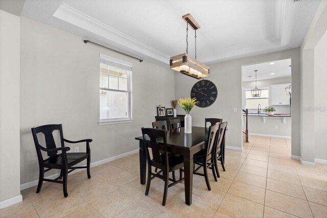 tiled dining space with a chandelier, a raised ceiling, and ornamental molding