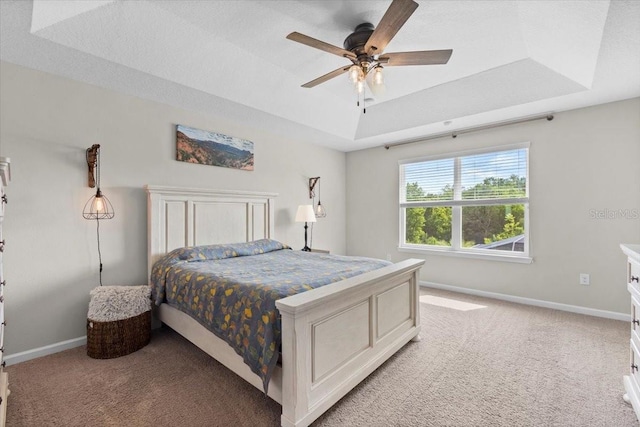 bedroom featuring light carpet, a raised ceiling, and ceiling fan