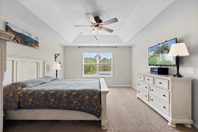 carpeted bedroom featuring ceiling fan, a textured ceiling, and a tray ceiling