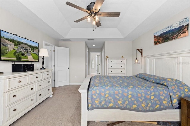 carpeted bedroom featuring ceiling fan and a tray ceiling