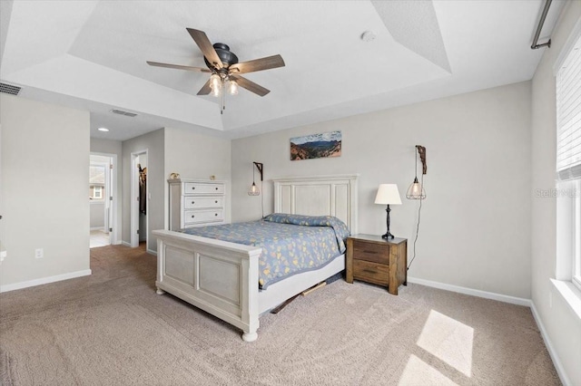 carpeted bedroom featuring multiple windows, a tray ceiling, and ceiling fan