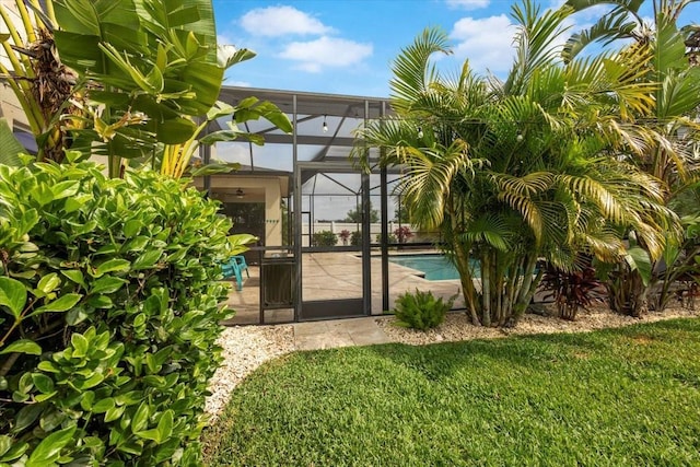 exterior space featuring a lanai, a lawn, and a patio