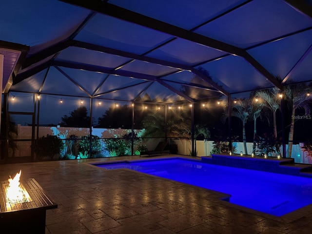 pool at twilight featuring a lanai and a patio