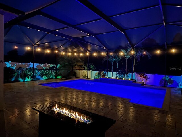 pool at twilight featuring an outdoor fire pit and a patio