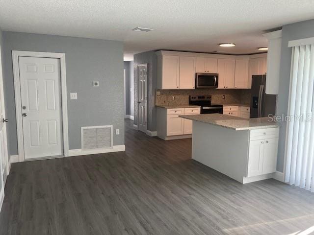 kitchen featuring white cabinetry, stainless steel appliances, dark hardwood / wood-style flooring, a textured ceiling, and decorative backsplash