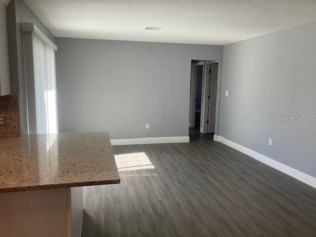 empty room with dark hardwood / wood-style flooring and a textured ceiling