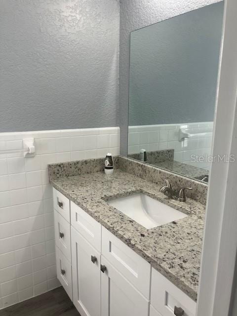 bathroom with hardwood / wood-style floors, vanity, and tile walls