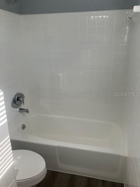 bathroom featuring hardwood / wood-style flooring, bathtub / shower combination, and toilet