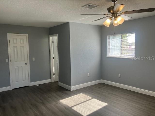 empty room featuring ceiling fan, dark hardwood / wood-style flooring, and a textured ceiling