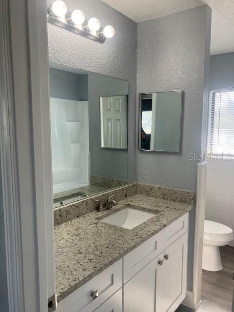 bathroom featuring a textured ceiling, vanity, hardwood / wood-style flooring, and toilet