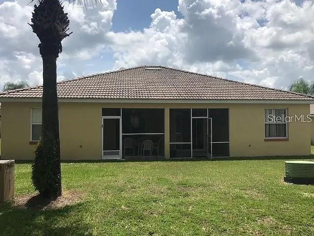 rear view of property with a yard, cooling unit, and a sunroom