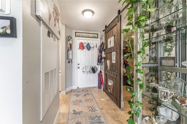 doorway featuring a barn door and a textured ceiling