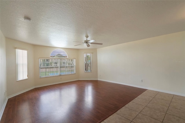 tiled empty room with a textured ceiling and ceiling fan