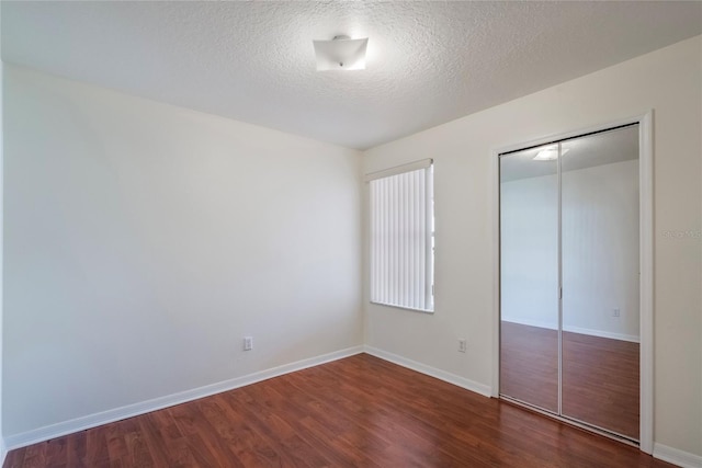 unfurnished bedroom featuring a closet, dark wood-type flooring, and a textured ceiling