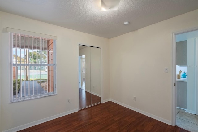 spare room with a textured ceiling and dark hardwood / wood-style floors