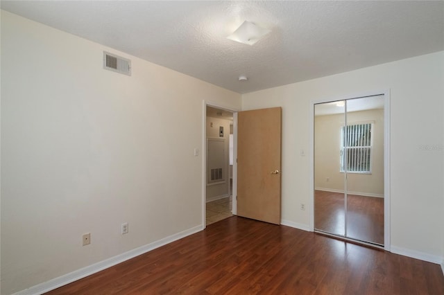 unfurnished bedroom with a closet, dark wood-type flooring, and a textured ceiling